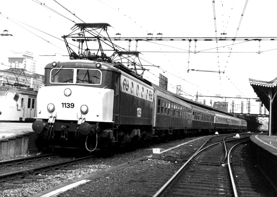 HUA-155035-Afbeelding van de electrische locomotief nr. 1139 (serie 1100) van de N.S. met D.B.-rijtuigen langs een perron van het N.S.-station Utrecht C.S. te Utrecht. De foto is gepubliceerd in de Koppeling, nr