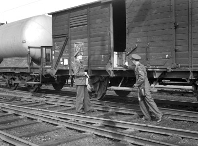 HUA-154253-Afbeelding van twee douaniers tijdens de grens controle van goederenwagens op het emplacement te Roosendaal
