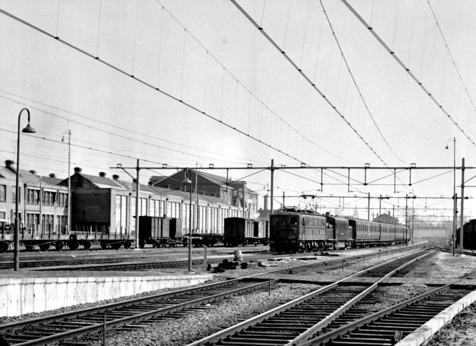 HUA-155243-Gezicht op het emplacement bij het NS station Tilburg te Tilburg met een trein getrokken door een door de NS gehuurde electrische locomotief uit de se