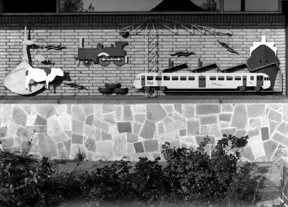 HUA-156063-Afbeelding van de door J.C. Borsje vervaardigde metaalplastiek "Giessendam vroeger en nu" aan de gevel van het N.S.-station Hardinxveld-Giessendam te Hardinxveld-Giessendam