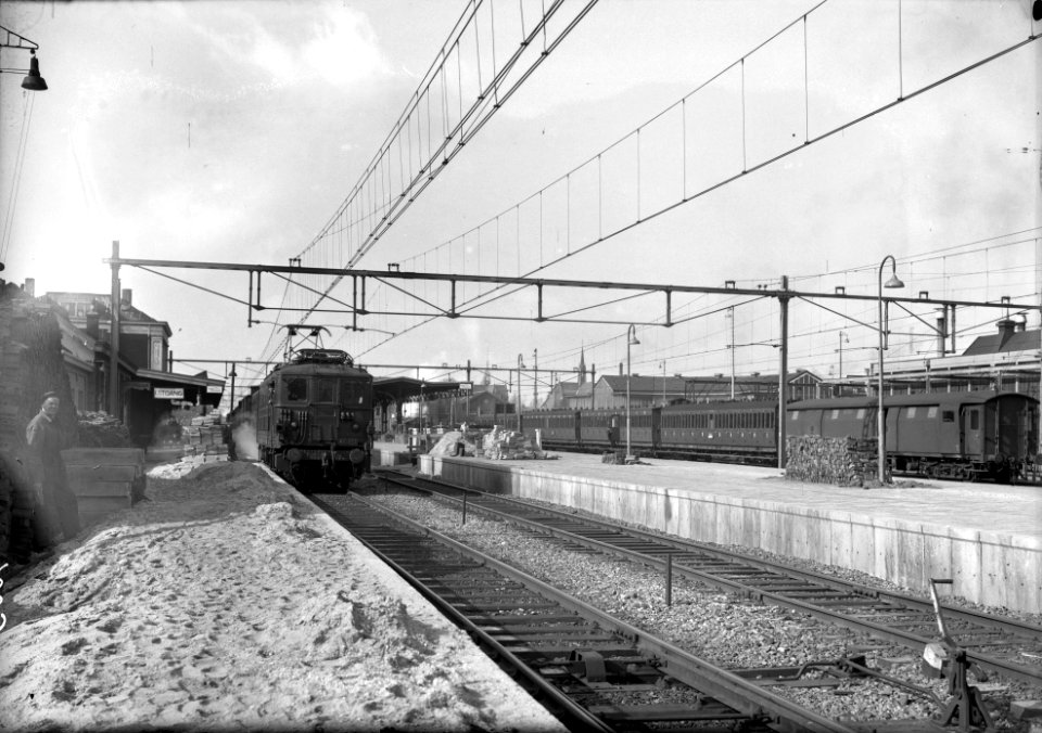 HUA-154666-Gezicht op de perrons van het N.S.-station Tilburg te Tilburg met links het stationsgebouw en de van de S.N.C.F. gehuurde electrische locomotief BB 322 (serie BB 300) van de N.S