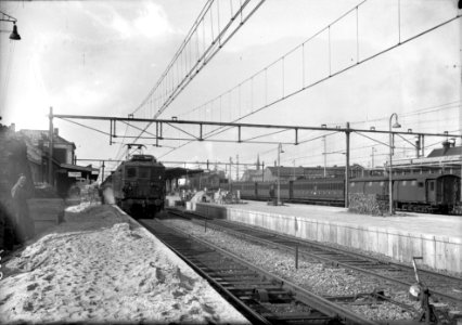 HUA-154666-Gezicht op de perrons van het N.S.-station Tilburg te Tilburg met links het stationsgebouw en de van de S.N.C.F. gehuurde electrische locomotief BB 322 (serie BB 300) van de N.S