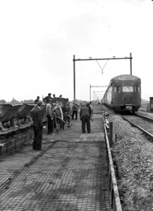 HUA-154273-Afbeelding van baanwerkers tijdens de heraanleg (baanverzwaring) van de spoorlijn Amsterdam-Utrecht nabij Abcoude met een diesel-electrisch treinstel DE 3 (serie 11-50) van de N.S