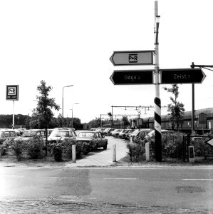 HUA-154539-Gezicht op de P+R-parkeerplaats bij het N.S.-station Driebergen-Zeist te Driebergen-Rijsenburg, met op de achtergrond een passerende ertstrein