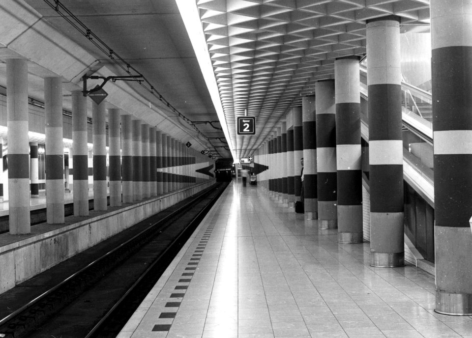 HUA-154067-Gezicht in de stationshal van het N.S.-station Schiphol te Amsterdam met de beschilderde kolommen van de kunstenaar M.J. Schwenke