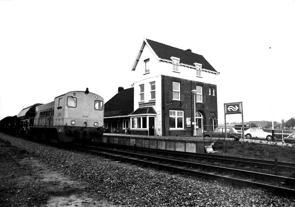 HUA-155881-Gezicht op de perronzijde van het N.S.-station Kropswolde te Kropswolde met links de diesel-electrische locomotief nr. 2293 (serie 2200-2300) van de N.S. met een goederentrein