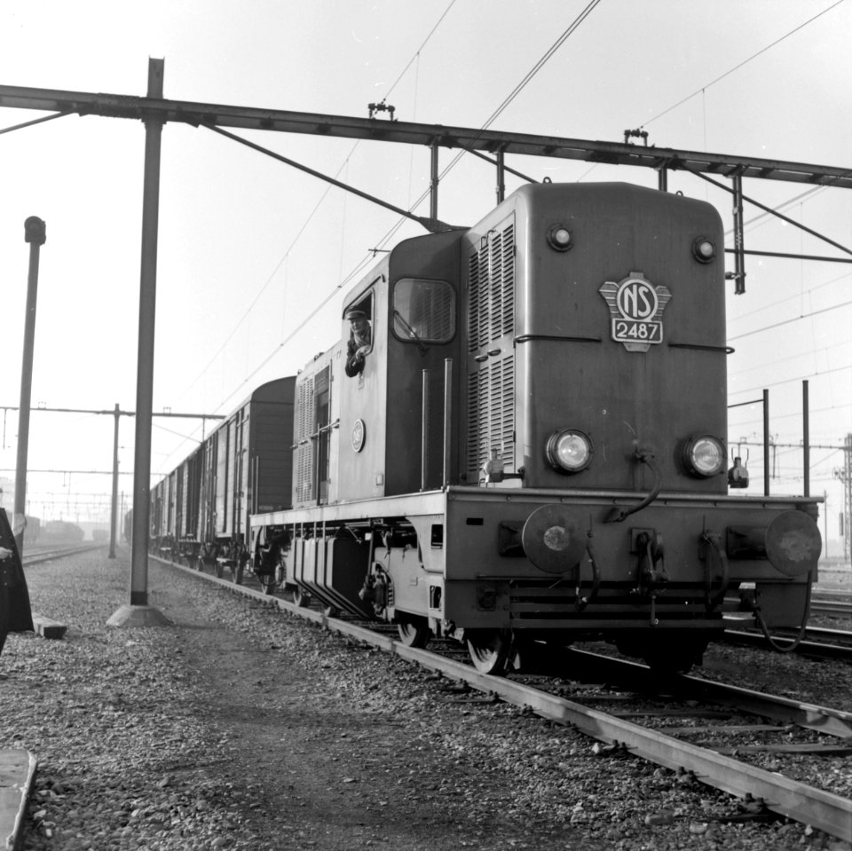 HUA-154303-Afbeelding van de diesel electrische locomotief nr 2487 serie 2400 2500 van de NS met een goederentrein op het emplacement te Lage Zwaluwe