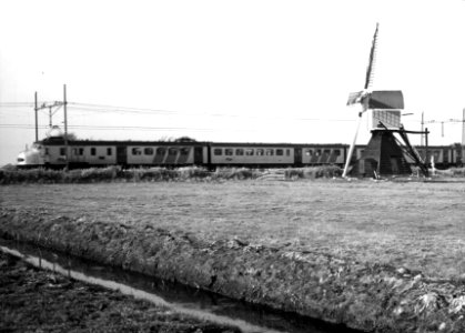 HUA-151049-Afbeelding van een electrisch treinstel mat. 1954 van de N.S. in een weidelandschap met molen bij Lisse