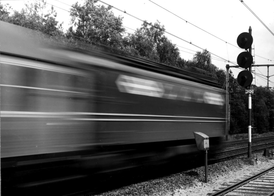 HUA-151047-Afbeelding van een voorbijsnellende buurlandtrein, getrokken door een electrische locomotief uit de serie 1100 van de N.S. op het emplacement te Maarn. Rechts een driehoogten-lichtsein