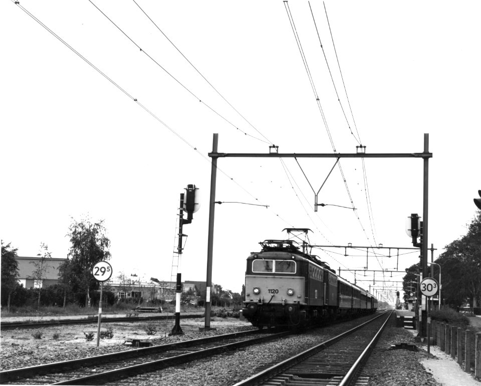 HUA-151076-Afbeelding van de electrische locomotief nr. 1120 (serie 1100) van de N.S met rijtuigen en een andere locomotief uit de serie 1100 in opzending bij het N.S.-station te Deurne