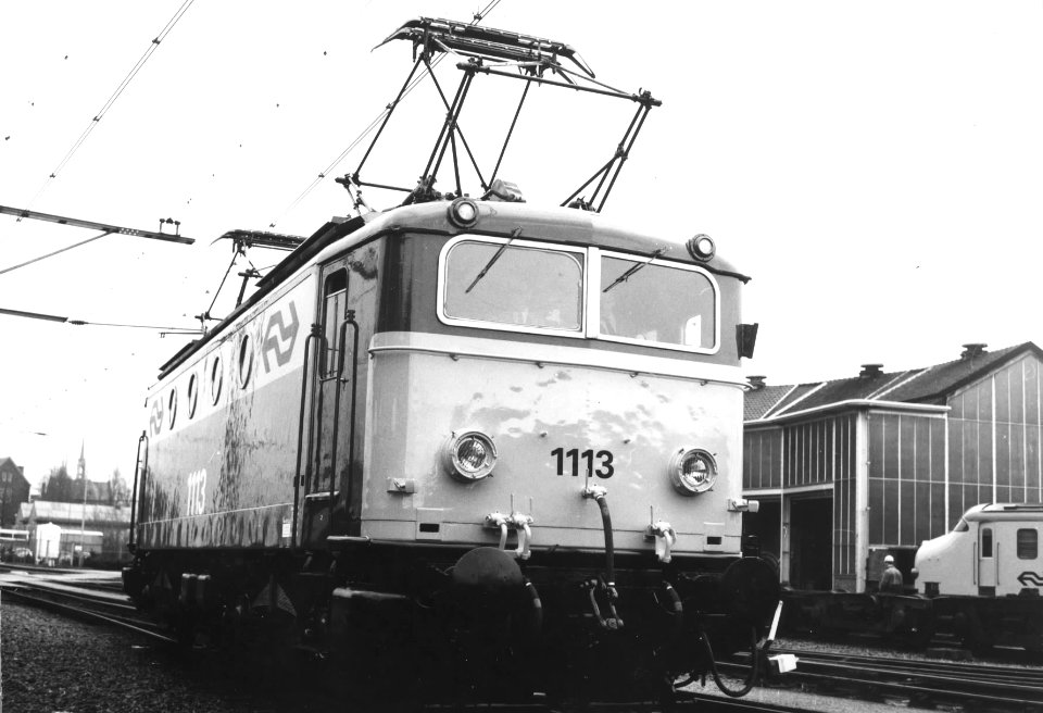 HUA-151131-Afbeelding van de electrische locomotief nr. 1113 (serie 1100) van de N.S. in nieuwe geel-grijze huisstijl bij de hoofdwerkplaats te Tilburg