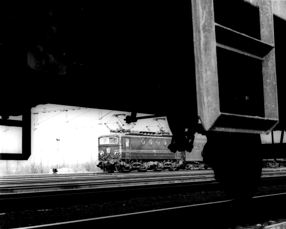 HUA-151116-Afbeelding van de electrische locomotief nr. 1138 (serie 1100) van de N.S., gezien onderdoor een goederenwagen