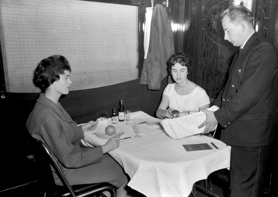 HUA-152223-Afbeelding van een kelner en twee treinreizigsters in een restauratierijtuig