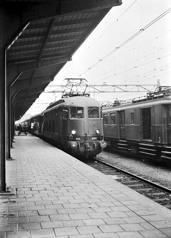 HUA-151099-Afbeelding van de electrische locomotief nr. 1004 (serie 1000) van de N.S. met internationale rijtuigen als Rheinpfeil langs het perron van het N.S.-station Hoek van Holland Haven te Hoek van Holland 
