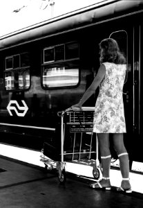 HUA-152029-Afbeelding van een vrouw met een witkar voor het vervoer van bagage op een perron van het N.S.-station Utrecht C.S
