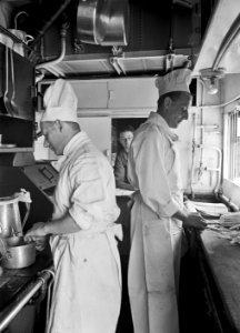 HUA-152212-Afbeelding van twee koks in de keuken van een restauratierijtuig van Wagons Lits, met links H.H. Jansen en rechts G. Krap die asperges schoonmaakt