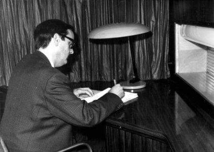 HUA-152339-Afbeelding van een man aan het bureau in de salon van het directierijtuig NS 20 ("Kameel") van de N.S