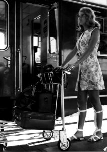 HUA-152028-Afbeelding van een vrouw met een witkar voor het vervoer van bagage op een perron van het N.S.-station Utrecht C.S