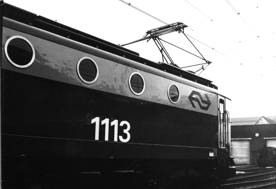 HUA-151126-Afbeelding van een gedeelte van de electrische locomotief nr. 1113 (serie 1100) van de N.S. in nieuwe huisstijl bij de hoofdwerkplaats te Tilburg