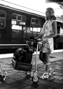 HUA-152027-Afbeelding van een vrouw met een witkar voor het vervoer van bagage op een perron van het N.S.-station Utrecht C.S