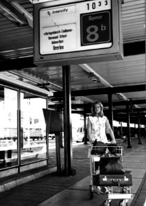 HUA-152026-Afbeelding van een vrouw met een witkar voor het vervoer van bagage op het perron van het NS station Utrecht CS te Utrecht Middenboven een centrale tr