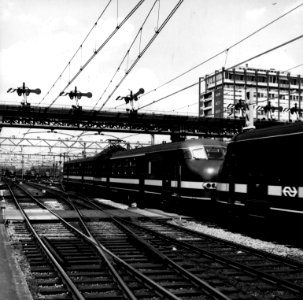 HUA-151719-Afbeelding van twee gekoppelde, electrische treinstellen mat. 1964 (plan V) van de N.S. onder de seinbrug van het N.S.-station Amsterdam C.S. (westzijde) te Amsterdam