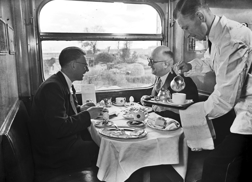 HUA-152211-Afbeelding van het interieur van een restauratierijtuig met twee treinreizigers (rechts de heer Van Bommel) en een kelner