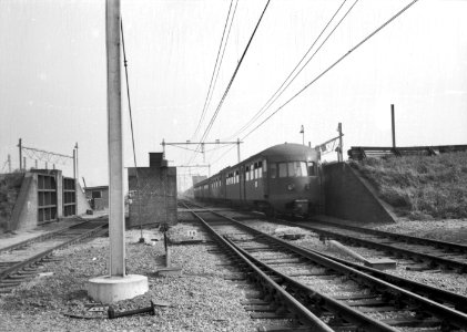 HUA-151190-Afbeelding van een diesel-electrisch treinstel DE 5 (serie 181-197, voorheen serie 51-68) van de N.S. door de dijkcoupure bij het N.S.-station Kruiningen-Yerseke