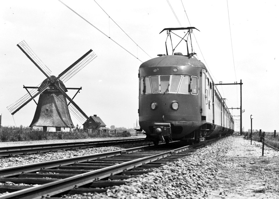 HUA-150905-Afbeelding van twee electrische treinstellen mat 1946 van de NS in een landschap met molen ter hoogte van Hazerswoude