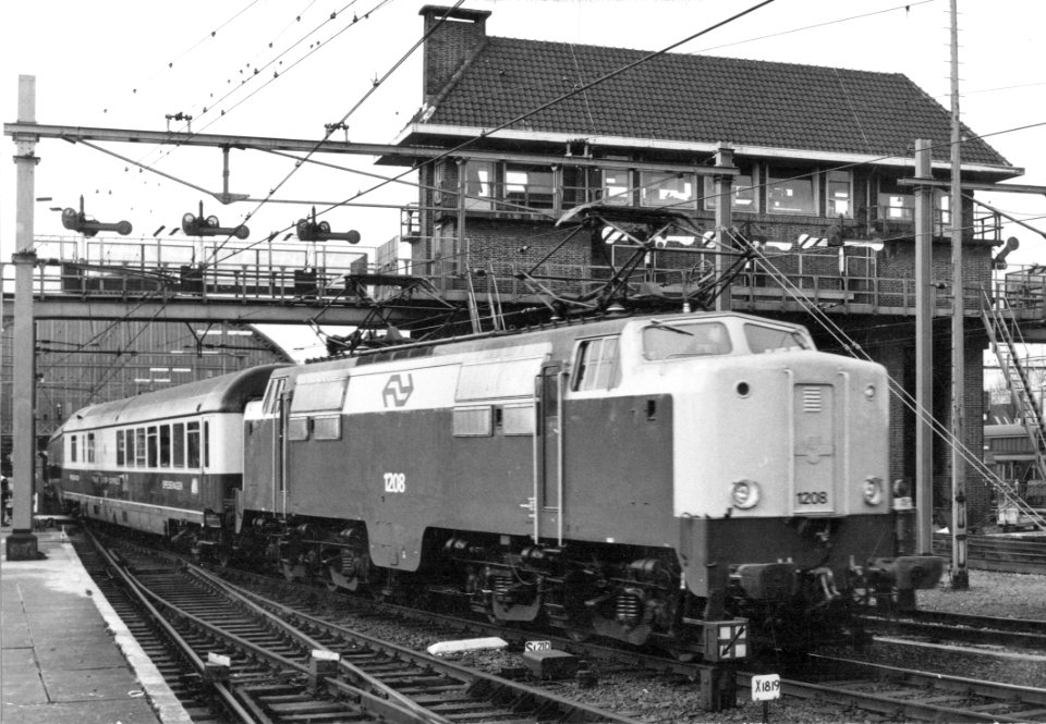 HUA-151158-Afbeelding van de electrische locomotief nr. 1208 (serie 1200) van de N.S. met internationale rijtuigen (T.E.E.) ter hoogte van het seinhuis bij het N.S.-station Amsterdam C.S. (oostzijde) te Amsterda