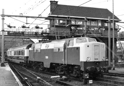 HUA-151158-Afbeelding van de electrische locomotief nr. 1208 (serie 1200) van de N.S. met internationale rijtuigen (T.E.E.) ter hoogte van het seinhuis bij het N.S.-station Amsterdam C.S. (oostzijde) te Amsterda