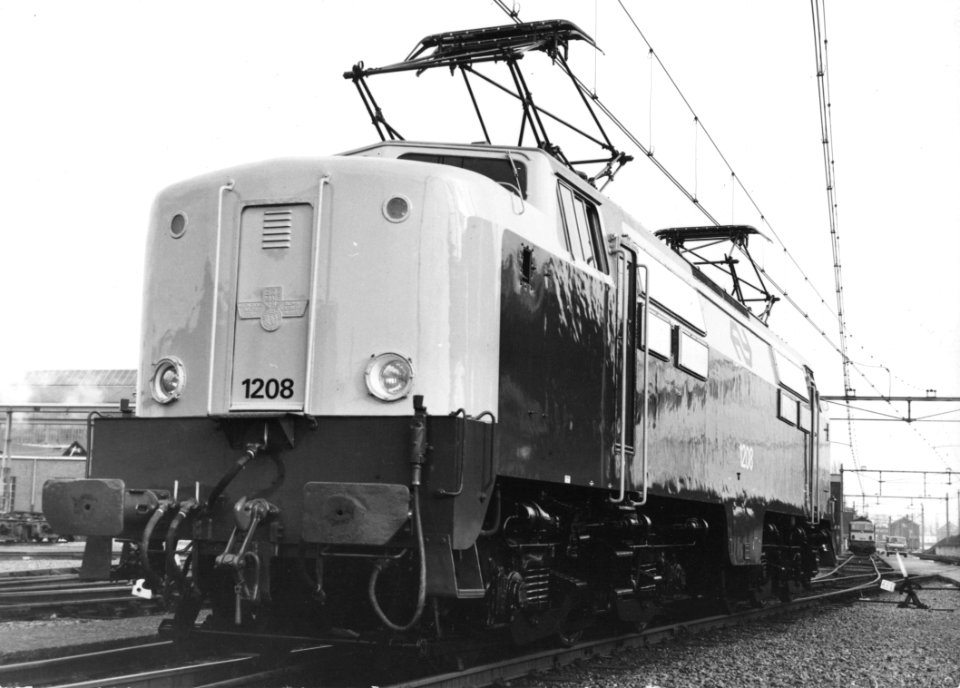HUA-151155-Afbeelding van de electrische locomotief nr. 1208 (serie 1200) van de N.S. in nieuwe geel-grijze huisstijl bij de hoofdwerkplaats van de N.S. te Tilburg