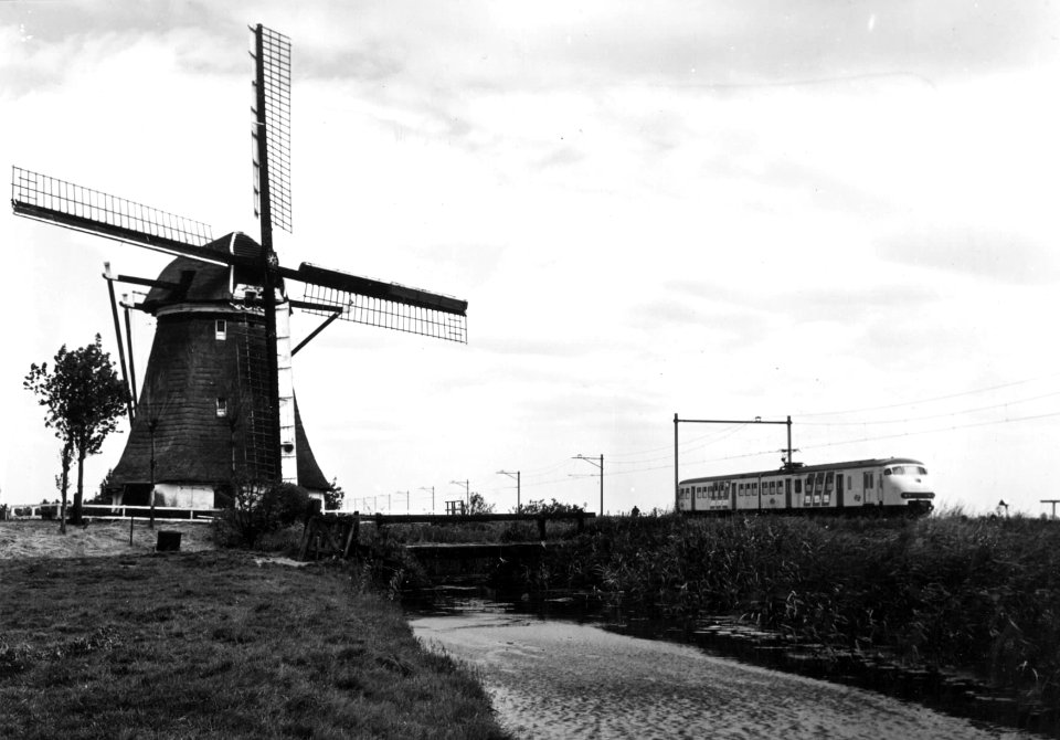 HUA-151020-Gezicht op een molen ter hoogte van Hazerswoude met op de achtergrond een electrisch treinstel mat. 1964 (plan V) van de N.S