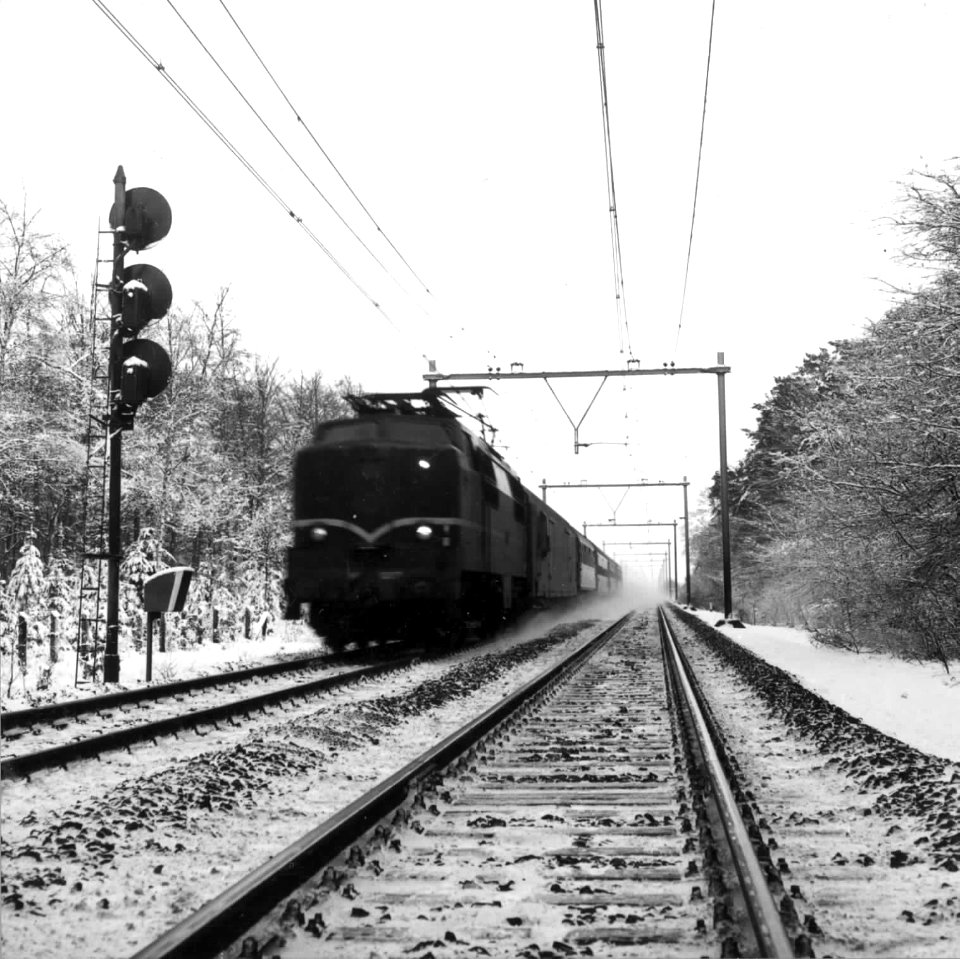 HUA-151002-Afbeelding van een electrische locomotief nr 1213 (serie 1200) met rijtuigen van de N.S. in de (besneeuwde) omgeving van Driebergen. Links een driehoogten-lichtsein
