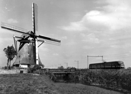 HUA-151019-Gezicht op een molen ter hoogte van Hazerswoude met op de achtergrond een electrisch treinstel mat 1964 plan V van de NS