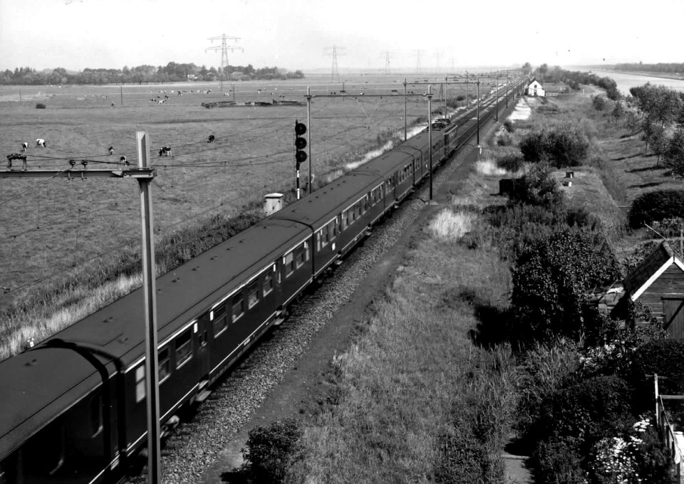 HUA-150982-Afbeelding van een electrische locomotief serie 1100 met rijtuigen van de NS ter hoogte van Loenen aan de Vecht Op de achtergrond het Amsterdam Rijnka