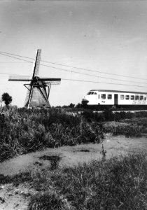HUA-151022-Gezicht op een molen en een passerend electrisch treinstel mat 1964 plan V van de NS ter hoogte van Hazerswoude