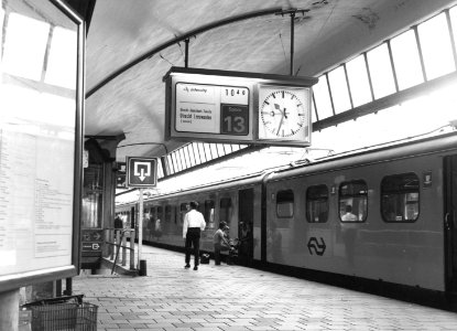 HUA-171316-Gezicht op het zesde perron van het N.S.-station Rotterdam C.S. te Rotterdam, met een centrale treinaanwijzer (CTA) en de intercity naar Leeuwarden (mat. 1954)