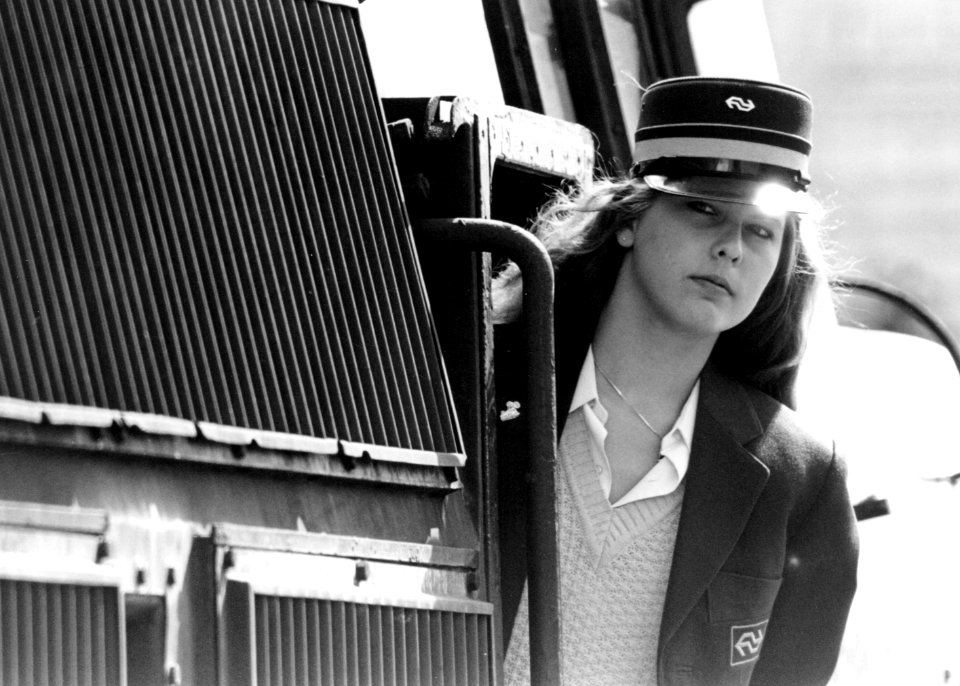 HUA-171760-Portret van een vrouwelijke machinist van de NS in de deuropening van een electrische locomotief uit de serie 1200