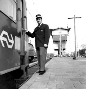 HUA-171736-Afbeelding van een machinist met het nieuwe uniform bij het electrische treinstel nr 504 mat 1964 plan T van de NS te Utrecht CS Op de achtergrond het