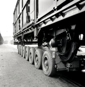 HUA-168088-Afbeelding van het vervoer van een goederenwagen van de N.S. op een oplegger van een vrachtauto ("wagon trailer" of "rolwagenvervoer") te Eindhoven