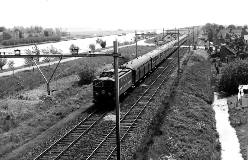 HUA-150983-Afbeelding van een electrische locomotief serie 1100 met rijtuigen van de NS ter hoogte van Loenen aan de Vecht Op de achtergrond het Amsterdam Rijnka