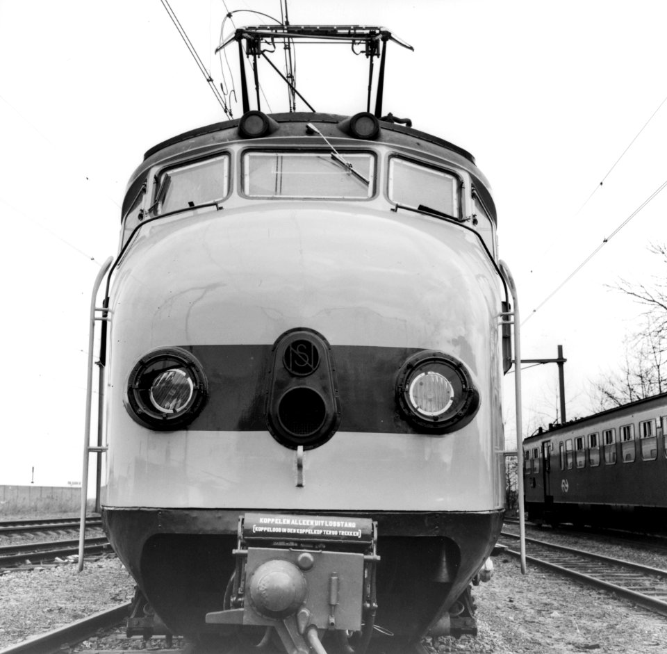 HUA-171803-Afbeelding van de kop van een electrisch treinstel mat 1954 plan G van de NS in de nieuwe geel grijze huisstijl op het terrein van de hoofdwerkplaats 
