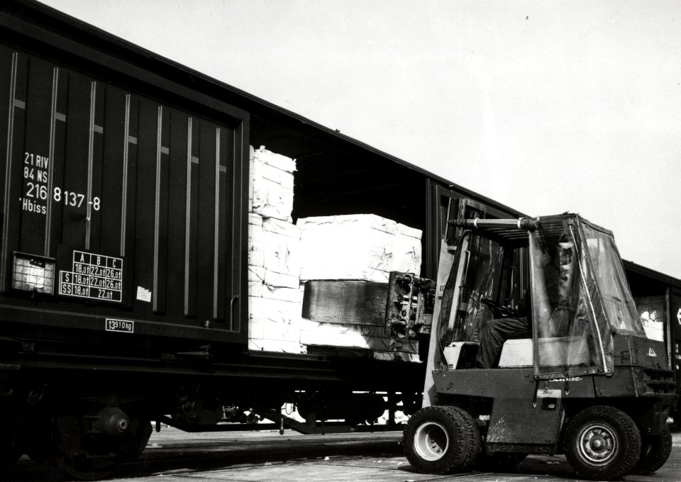 HUA-171230-Afbeelding van het beladen van goederenwagens (schuifwandwagen) type Hbiss van de N.S. met behulp van een heftruck met papier te Eerbeek