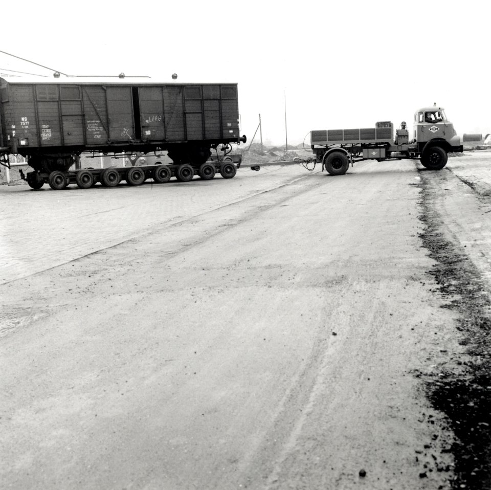 HUA-168102-Afbeelding van het vervoer van een goederenwagen van de N.S. op een oplegger van een vrachtauto ("wagon trailer" of "rolwagenvervoer") te Eindhoven