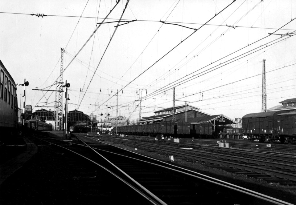 HUA-159885-Gezicht op de stukgoederenloods van Van Gend & Loos met gesloten goederenwagens ("geelbanders") van de N.S. bij het N.S.-station Den Haag S.S. te Den Haag