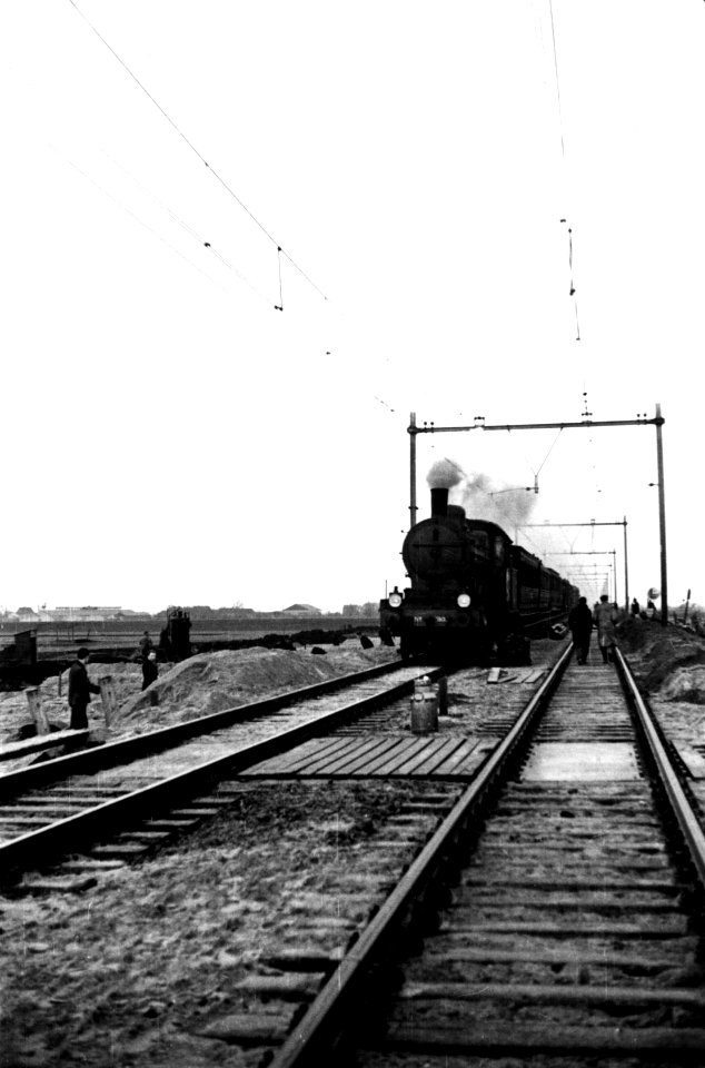 HUA-160417-Afbeelding van de grondwerkzaamheden aan de spoorlijn tussen Gouda en Oudewater, tijdens het passeren van een trein getrokken door een stoomlocomotief uit de serie 3700-3800 van de N.S