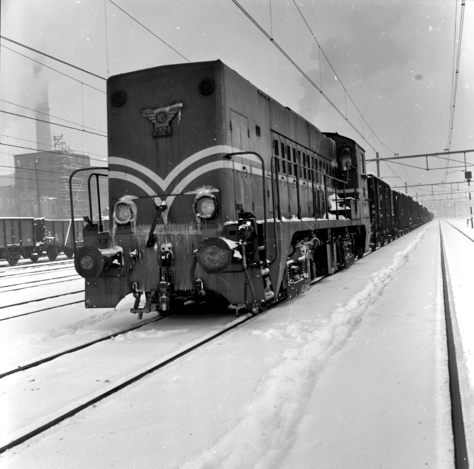 HUA-159804-Afbeelding van de diesel-electrische locomotief nr. 2321 (serie 2200-2300) van de N.S. met een kolentrein op het besneeuwde emplacement te Heerlen