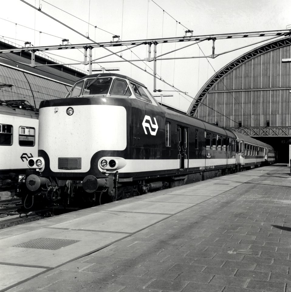 HUA-168174-Afbeelding van een electrische Benelux trek duweenheid van de NS en de NMBS langs het perron van het NS station Amsterdam CS te Amsterdam