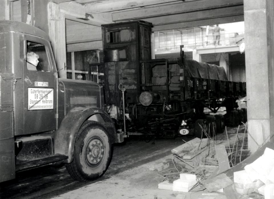 HUA-168052-Afbeelding van een vrachtauto van de Deutsche Bundesbahn DB met een aanhangwagen waarop een spoorwagon rongenwagen vervoerd wordt Strassenroller te Wo